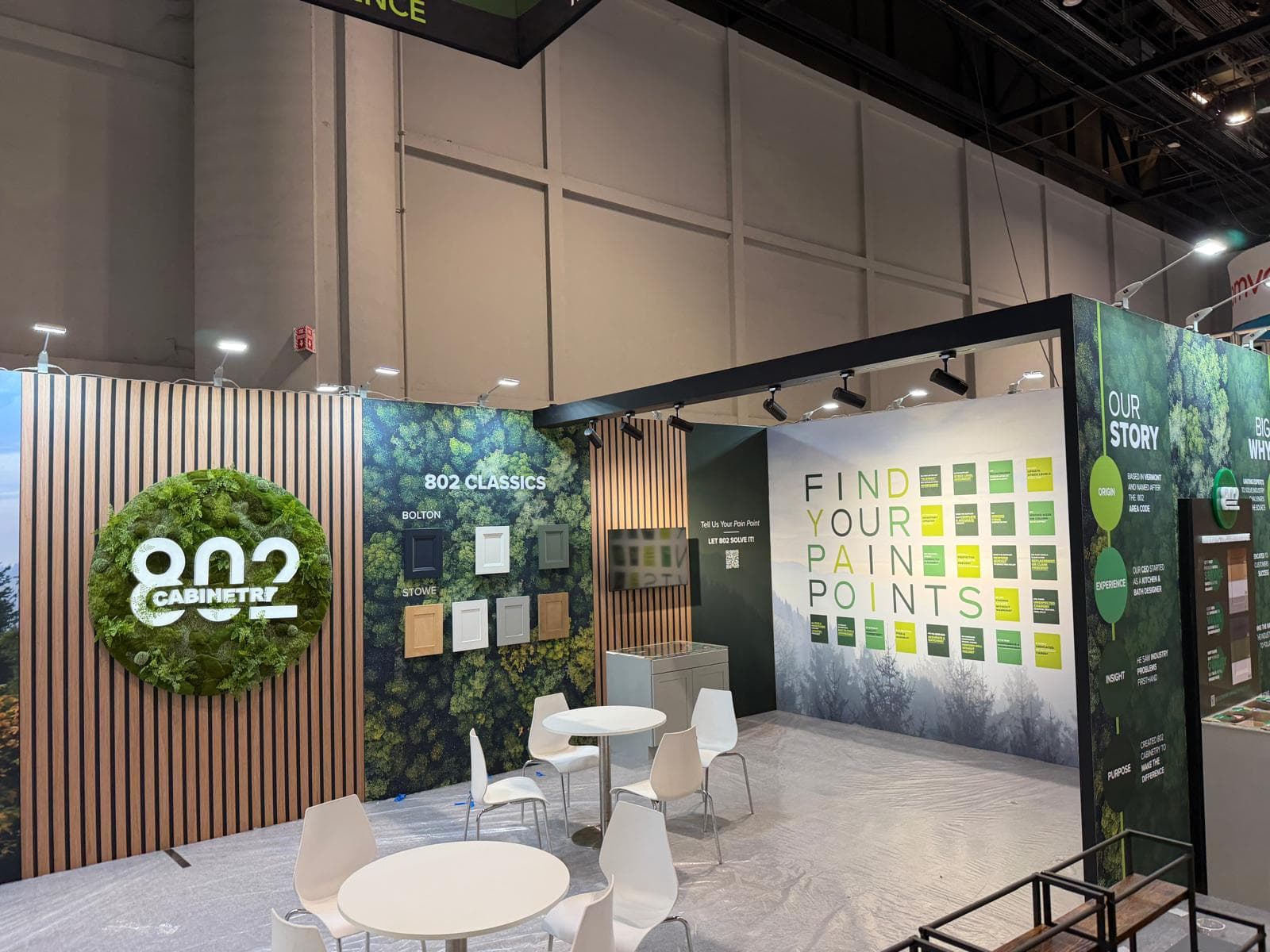 Trade show booth for 802 Cabinetry featuring wood slats, forest graphics, and cabinet samples.